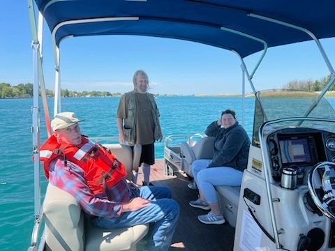 A group of people are sitting on a pontoon boat on a lake.