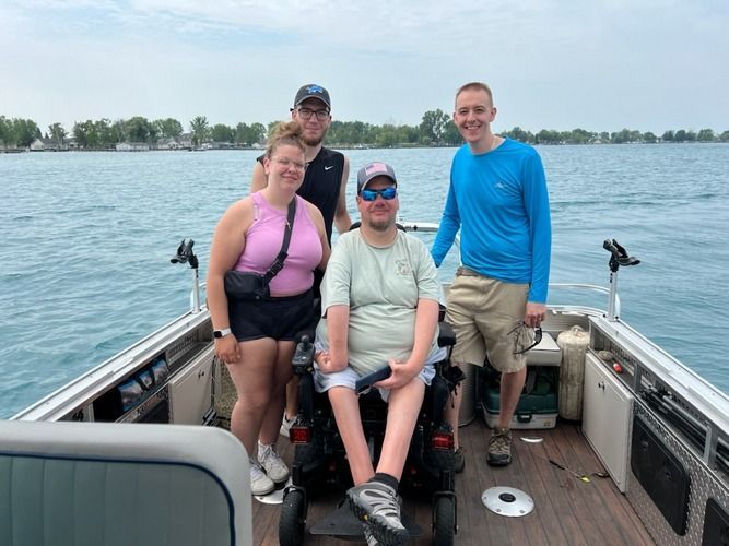 A man in a wheelchair is sitting on the back of a boat with other people.