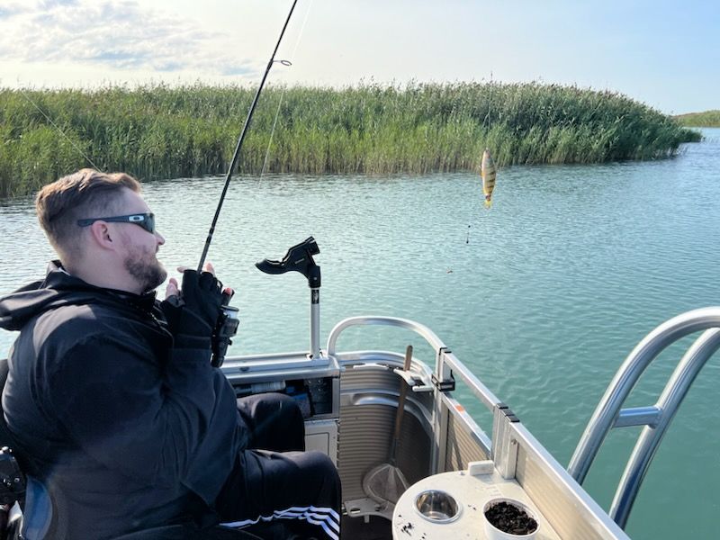 A man is fishing on a boat in the water.