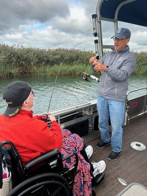 A man and a woman in a wheelchair are fishing on a boat.