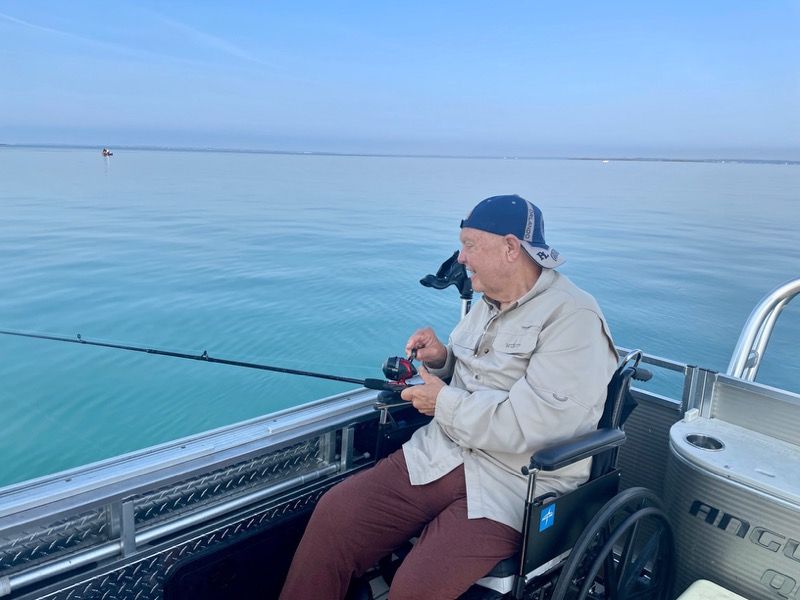 A man in a wheelchair is fishing on a boat.