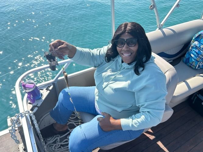 A woman is sitting on a boat holding a fish in her hand.