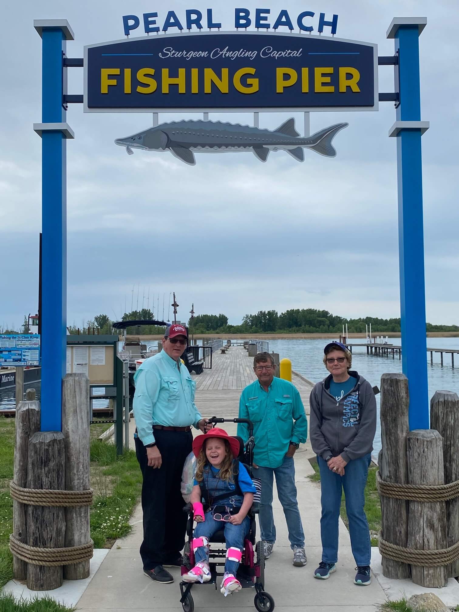 A group of people standing under a sign that says pearl beach fishing pier