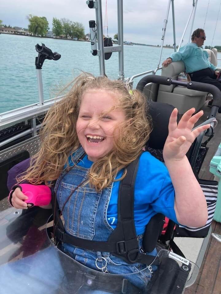 A young girl is sitting in a wheelchair on a boat.