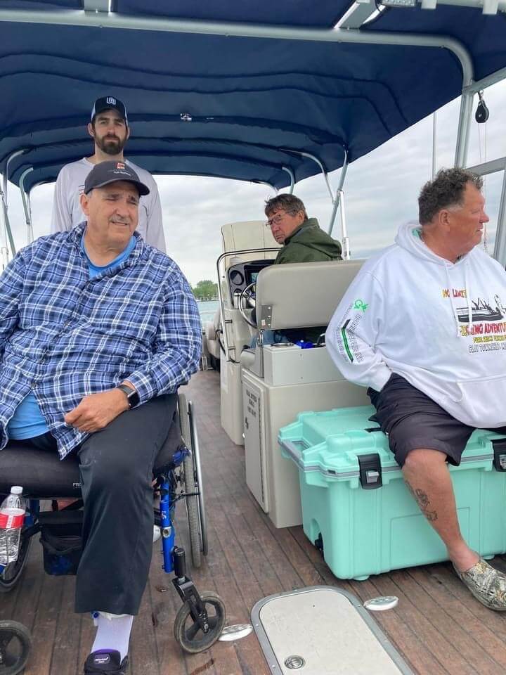 A man in a wheelchair is sitting on a boat with other men.