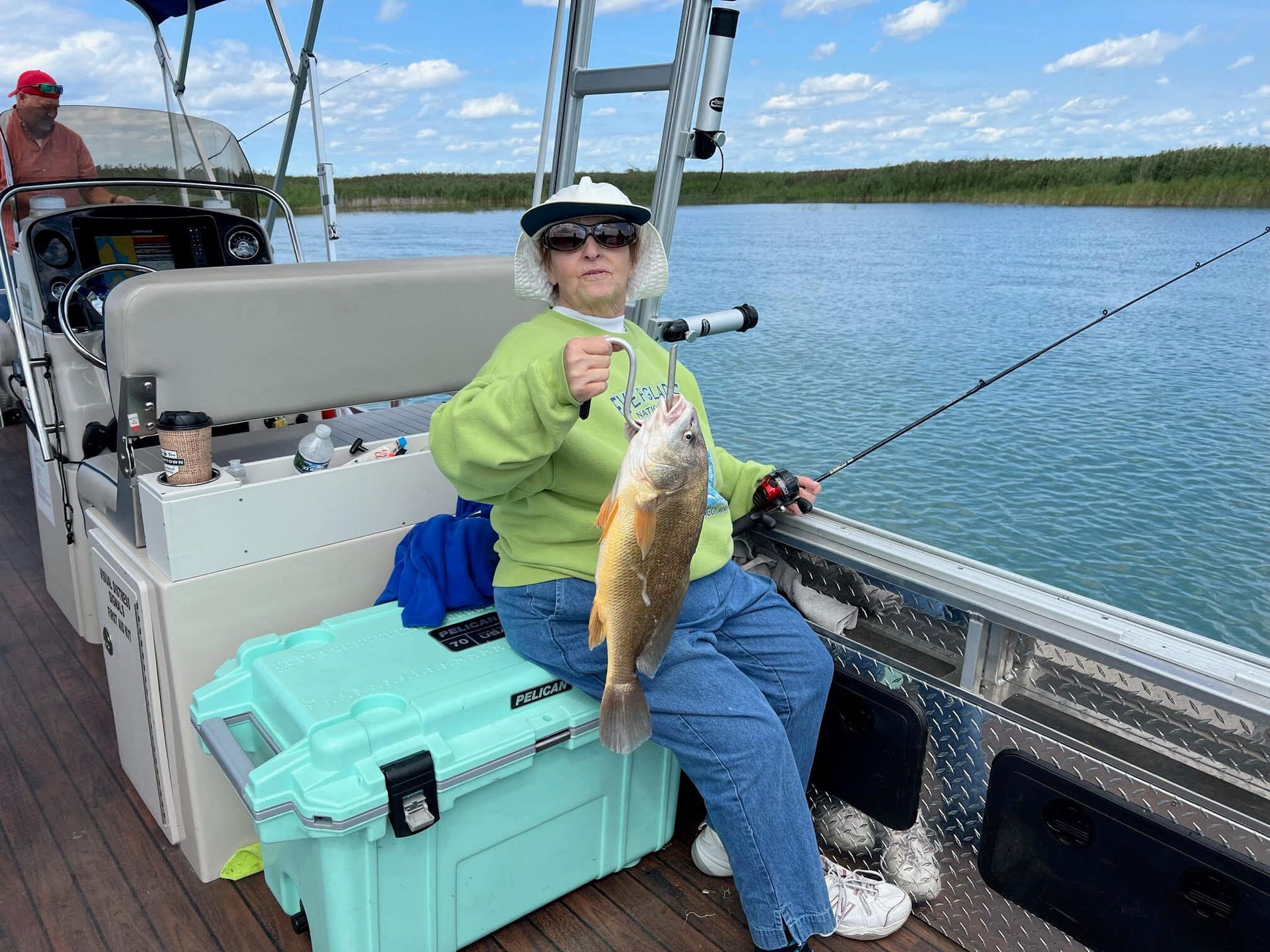 A woman is sitting on a boat holding a fish.