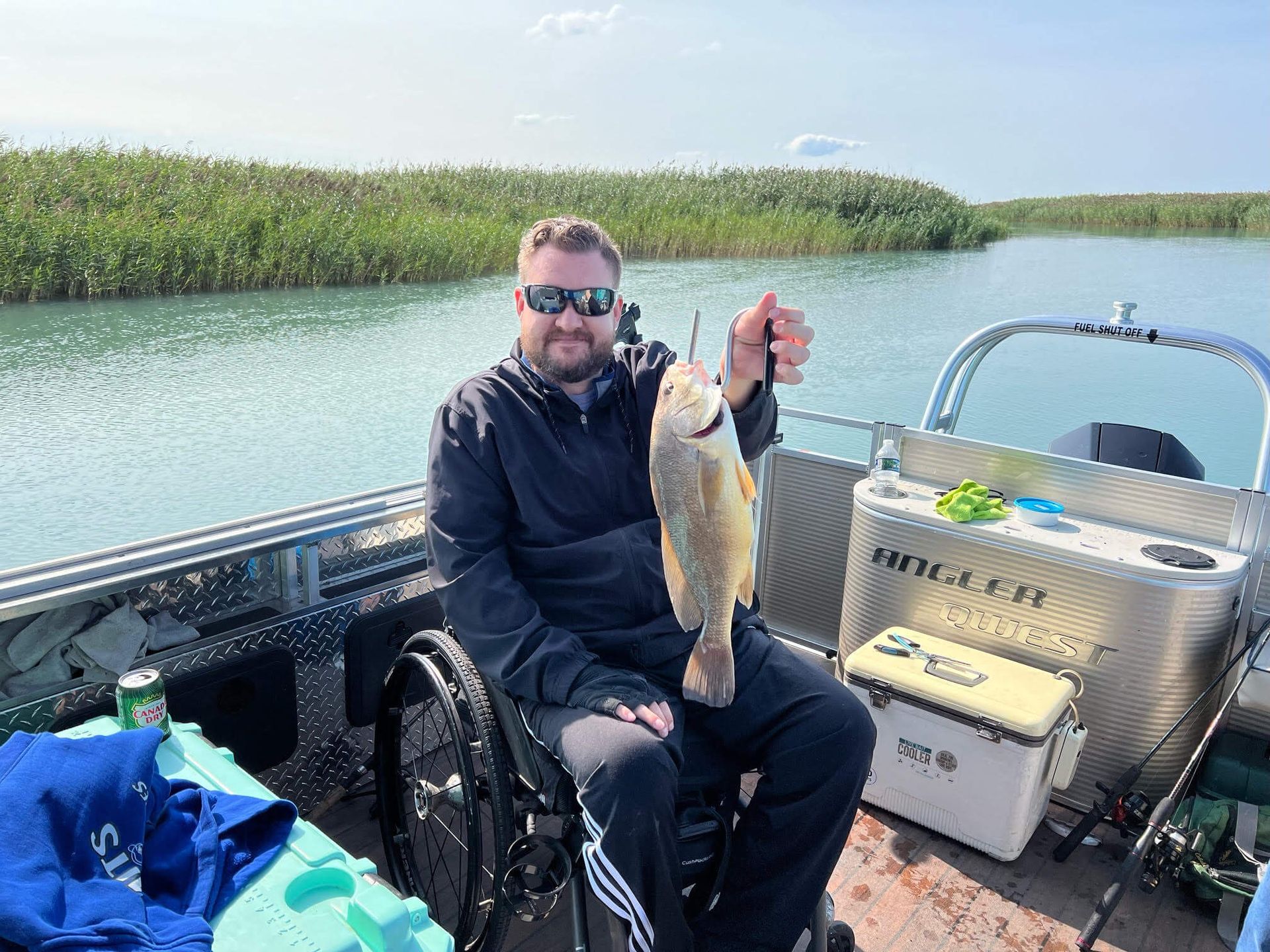 A man in a wheelchair is sitting on a boat holding a fish.
