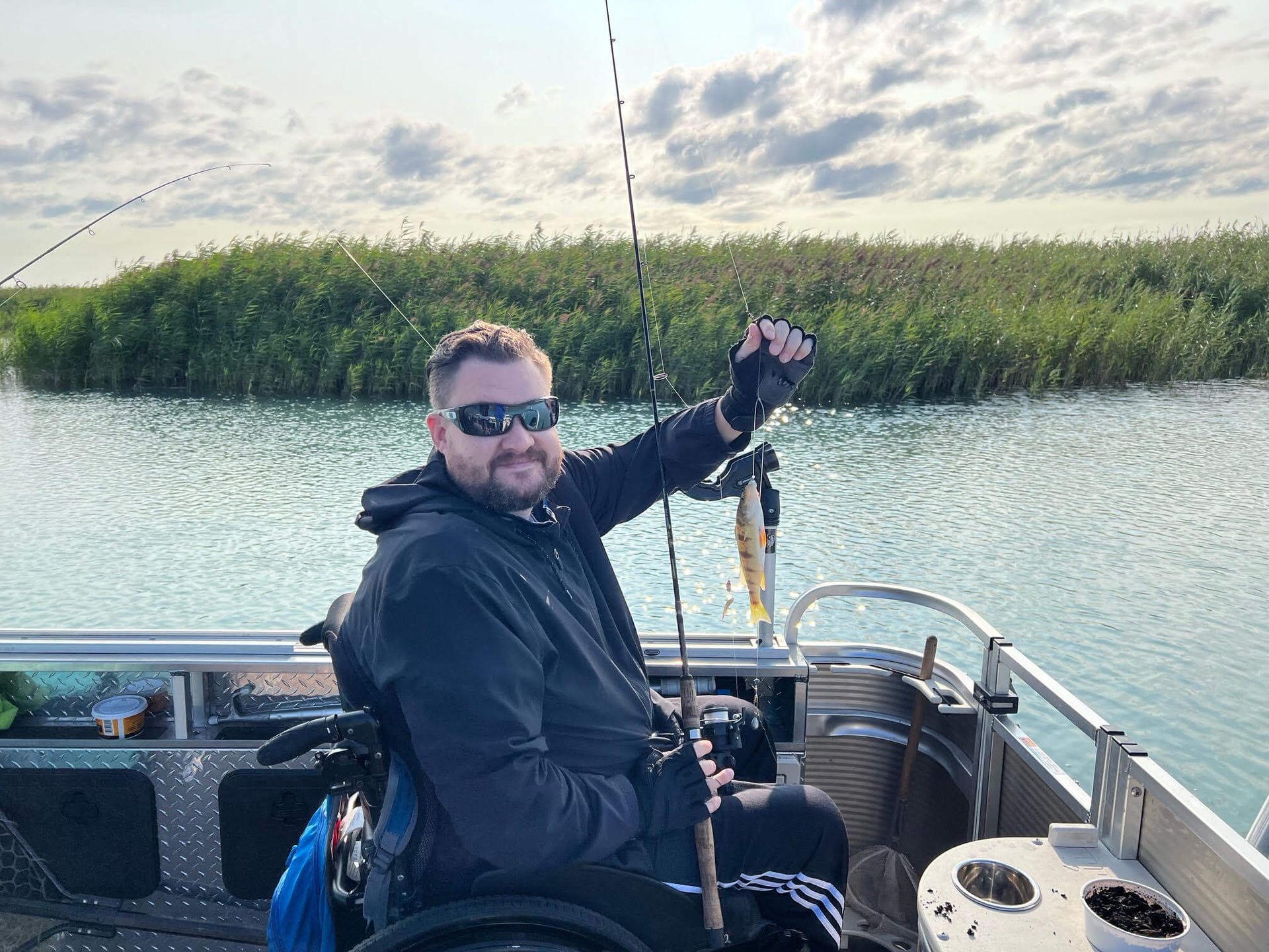 A man in a wheelchair is fishing on a boat.