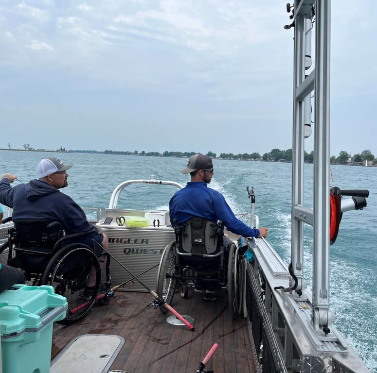 A man in a wheelchair is sitting on the deck of a boat