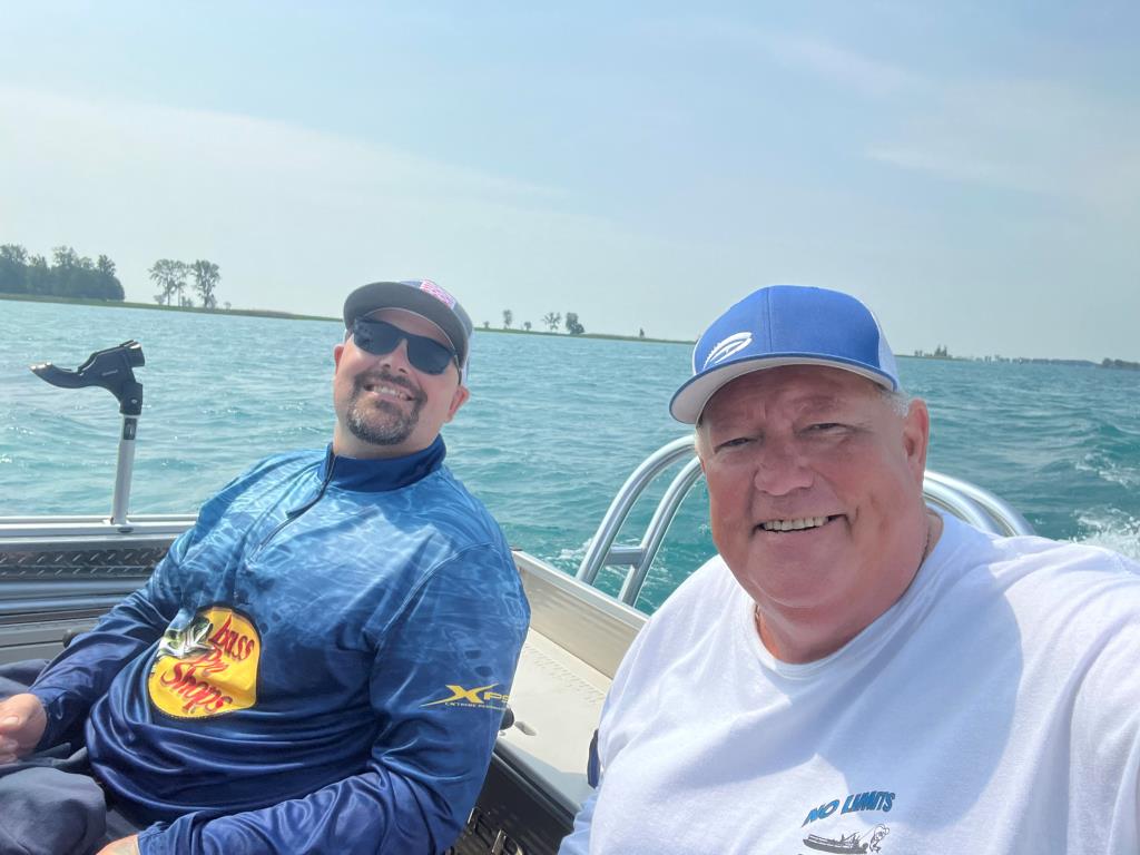 Two men are sitting on a boat in the water.