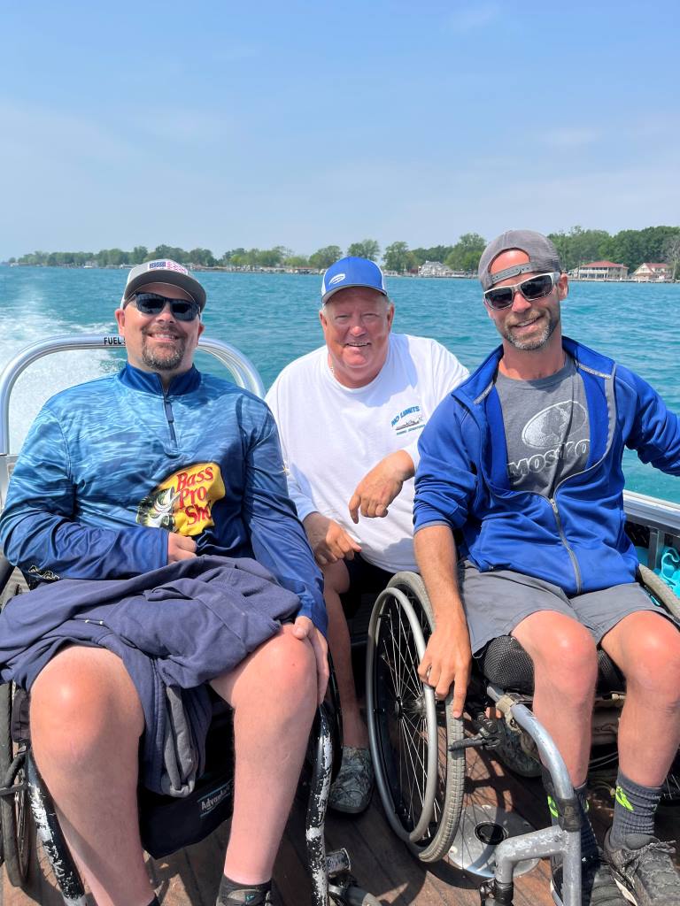 Three men in wheelchairs are sitting on a boat.