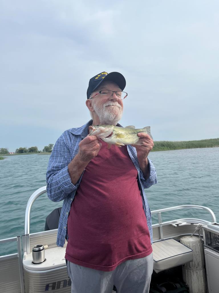 A man is standing on a boat holding a fish in his hands.