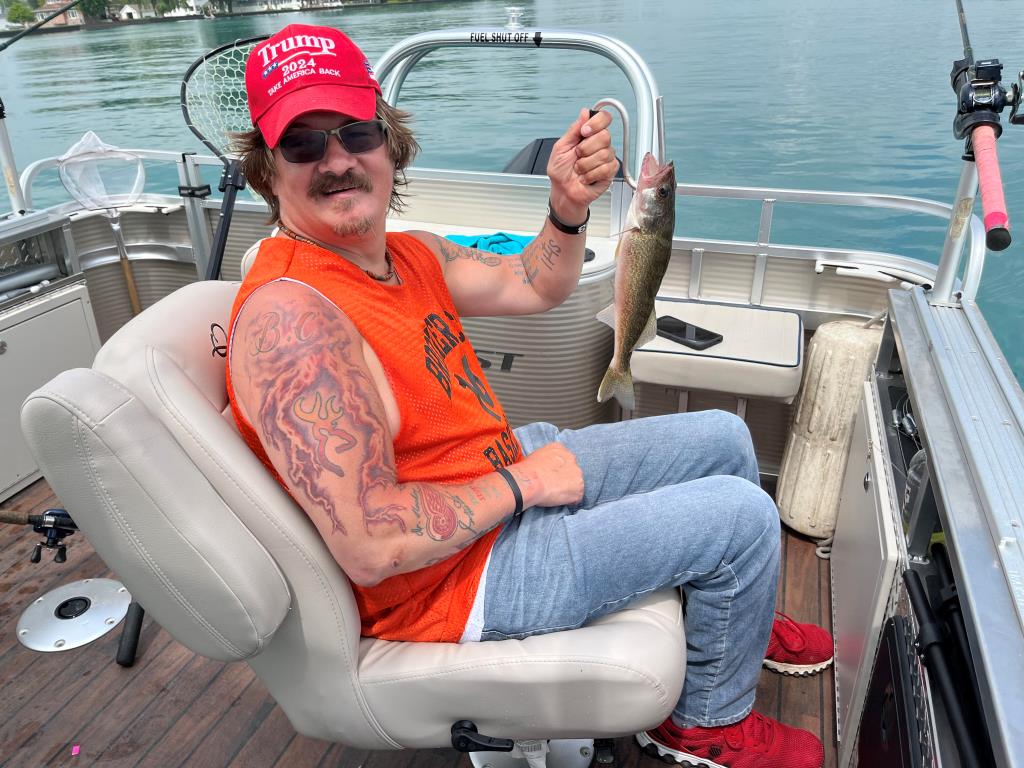 A man is sitting on a boat holding a fish.