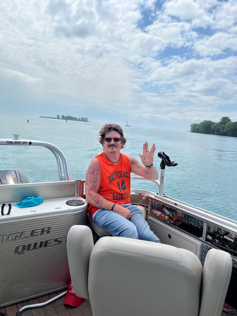 A man is sitting on a boat in the water.
