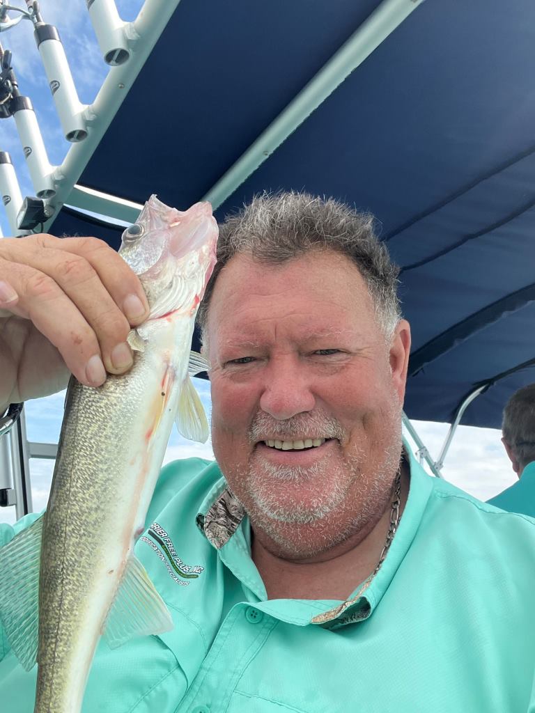 A man is holding a fish in his hand on a boat.