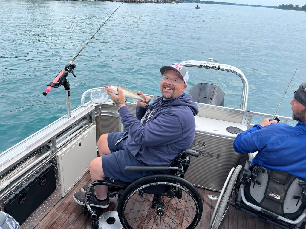 A man in a wheelchair is fishing on a boat.
