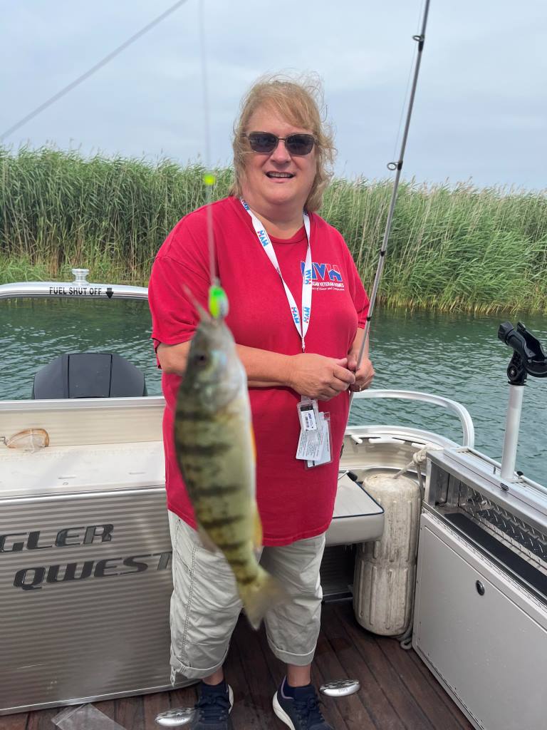 A woman is standing on a boat holding a fish.