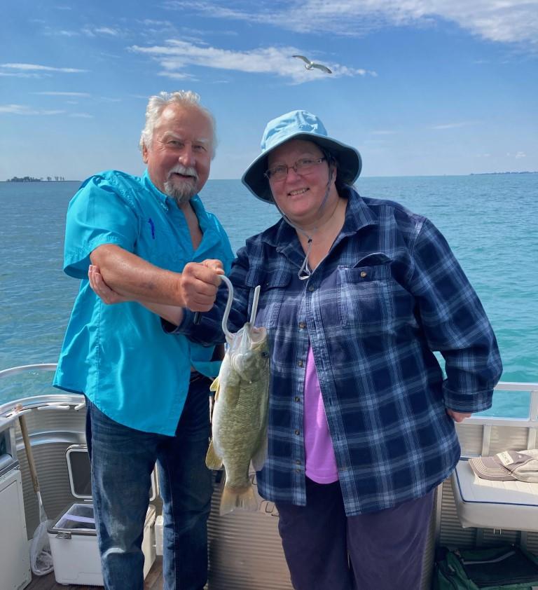 A man and a woman standing on a boat holding fish