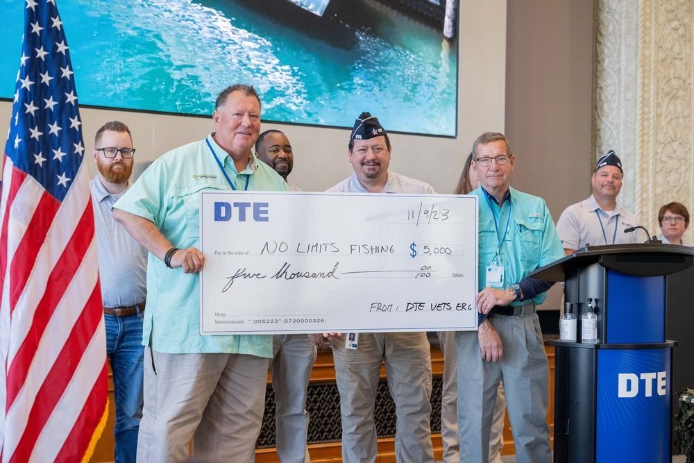 A group of men holding a large check awarded from DTE for service to the veteran community.