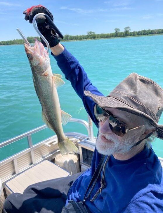 A man on a boat holding a fish in his hand