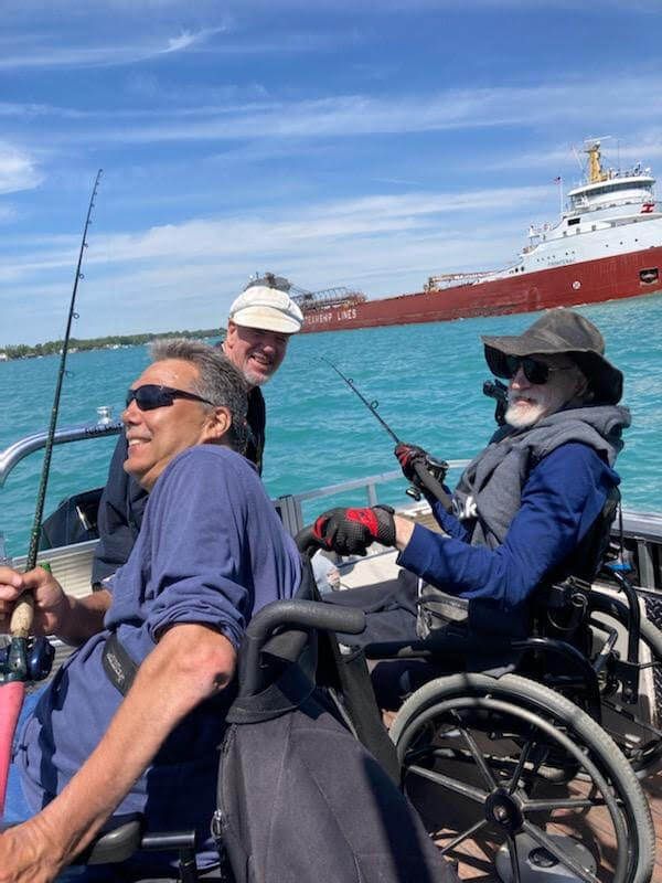 A group of people in wheelchairs are fishing on a boat.