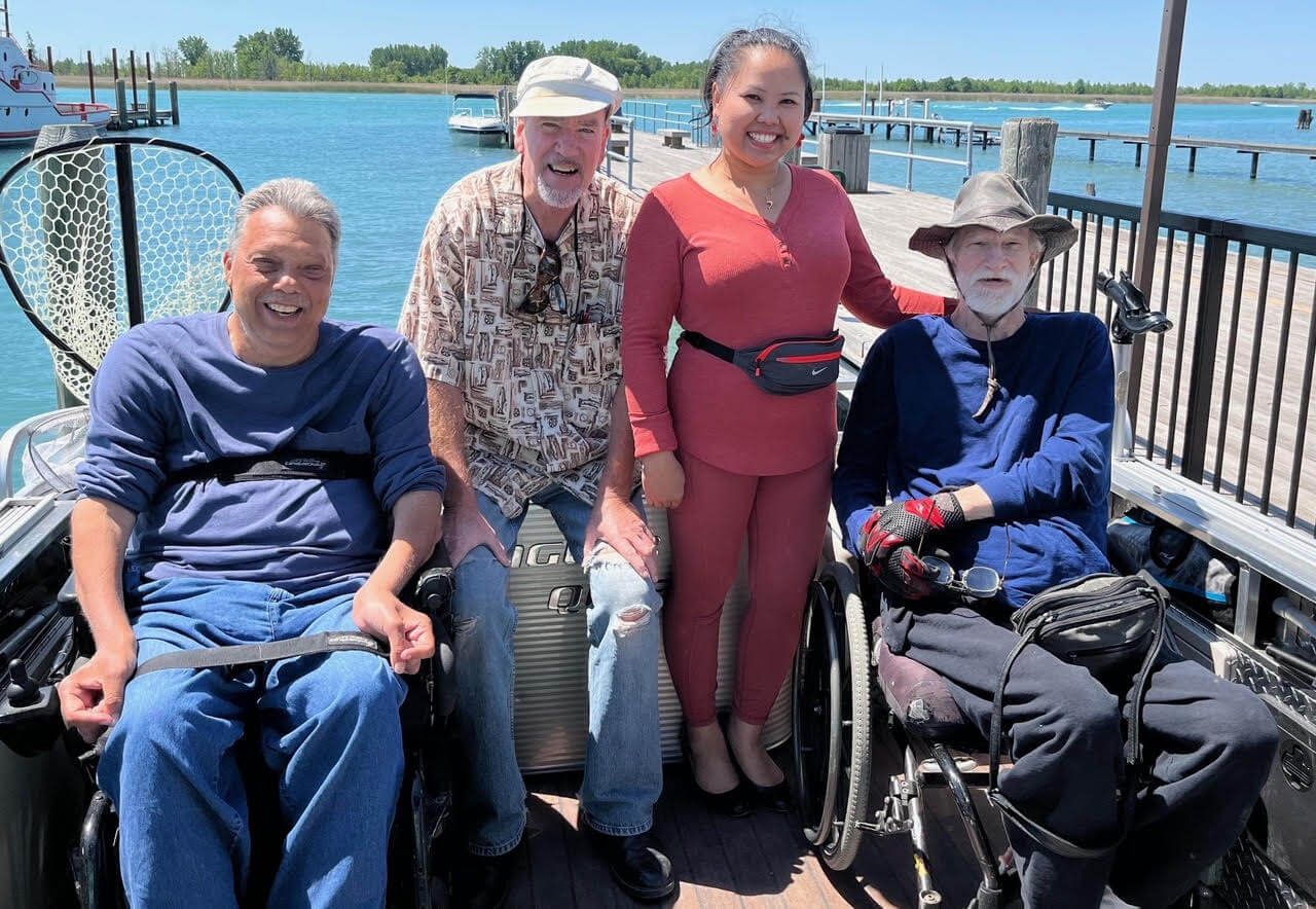 A group of people in wheelchairs are posing for a picture on a boat.