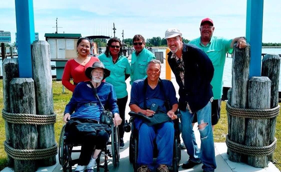 A group of people posing for a picture with one man in a wheelchair.