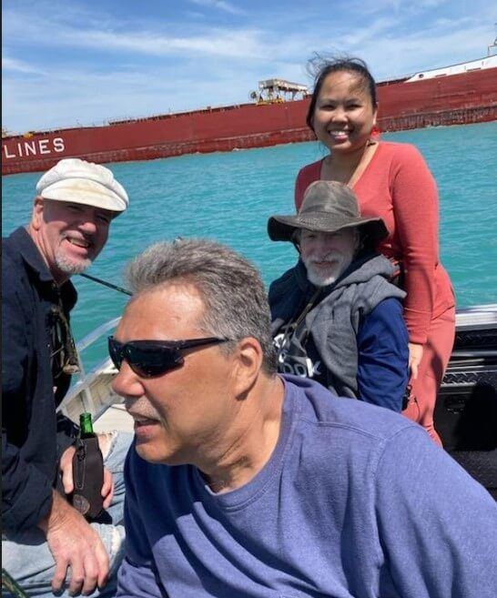 A group of people on a boat with a ship in the background that says lines