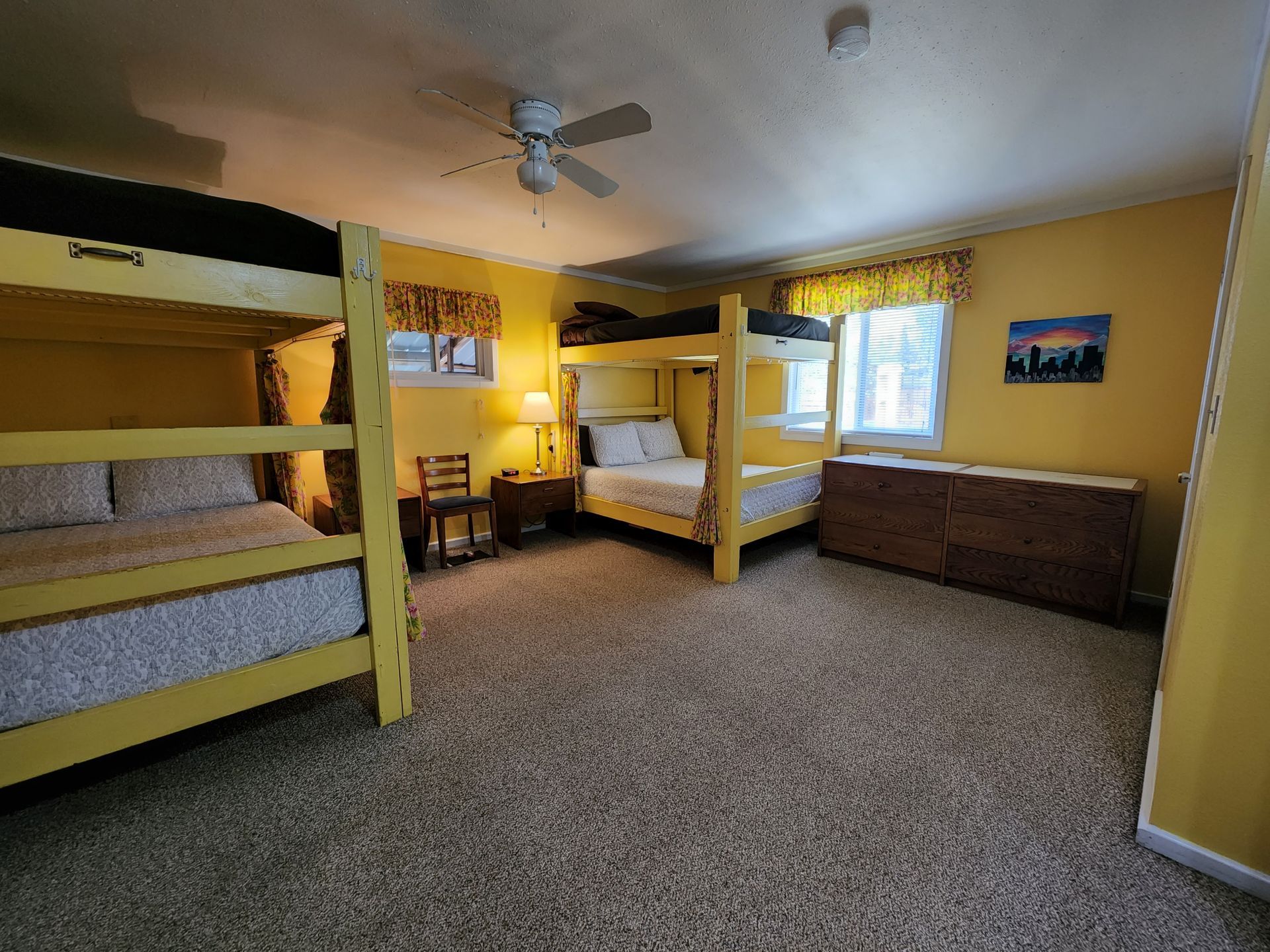 A bedroom with bunk beds , a dresser , and a ceiling fan.