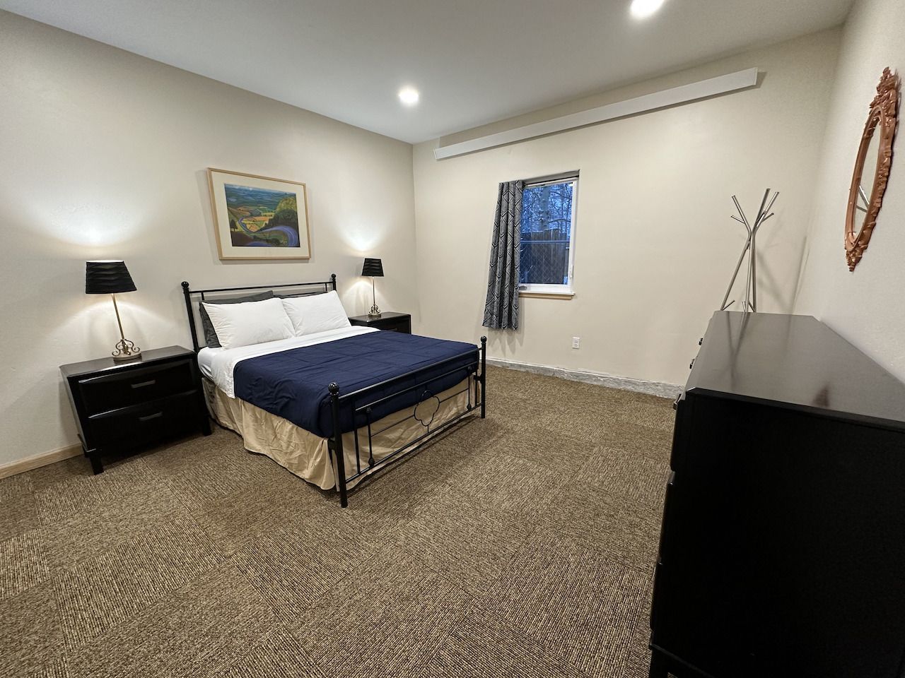 A bedroom with a bed lamps and a picture on the wall