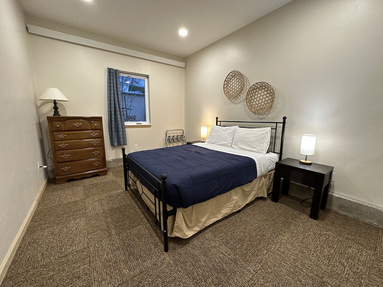 A bedroom with a bed , two nightstands and two lamps.