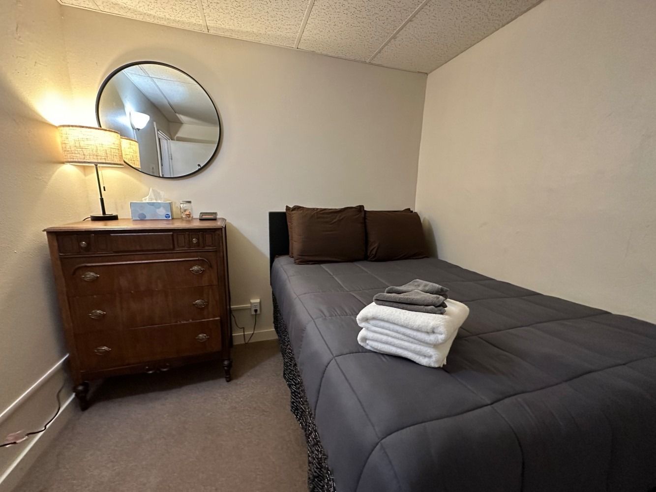 A bedroom with a bed , dresser and mirror