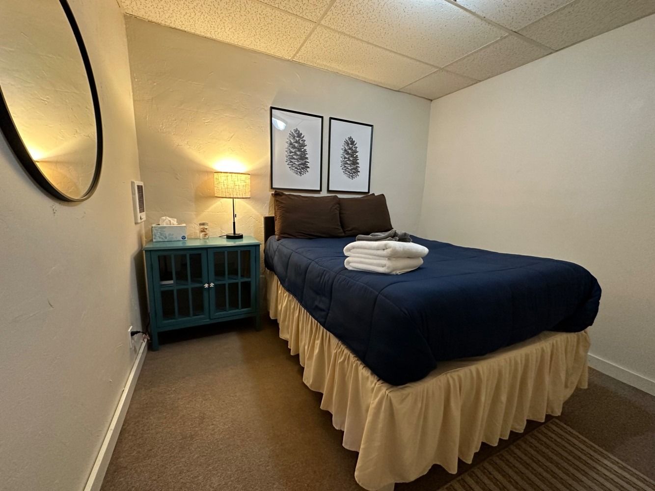 A bedroom with a bed , nightstand and mirror