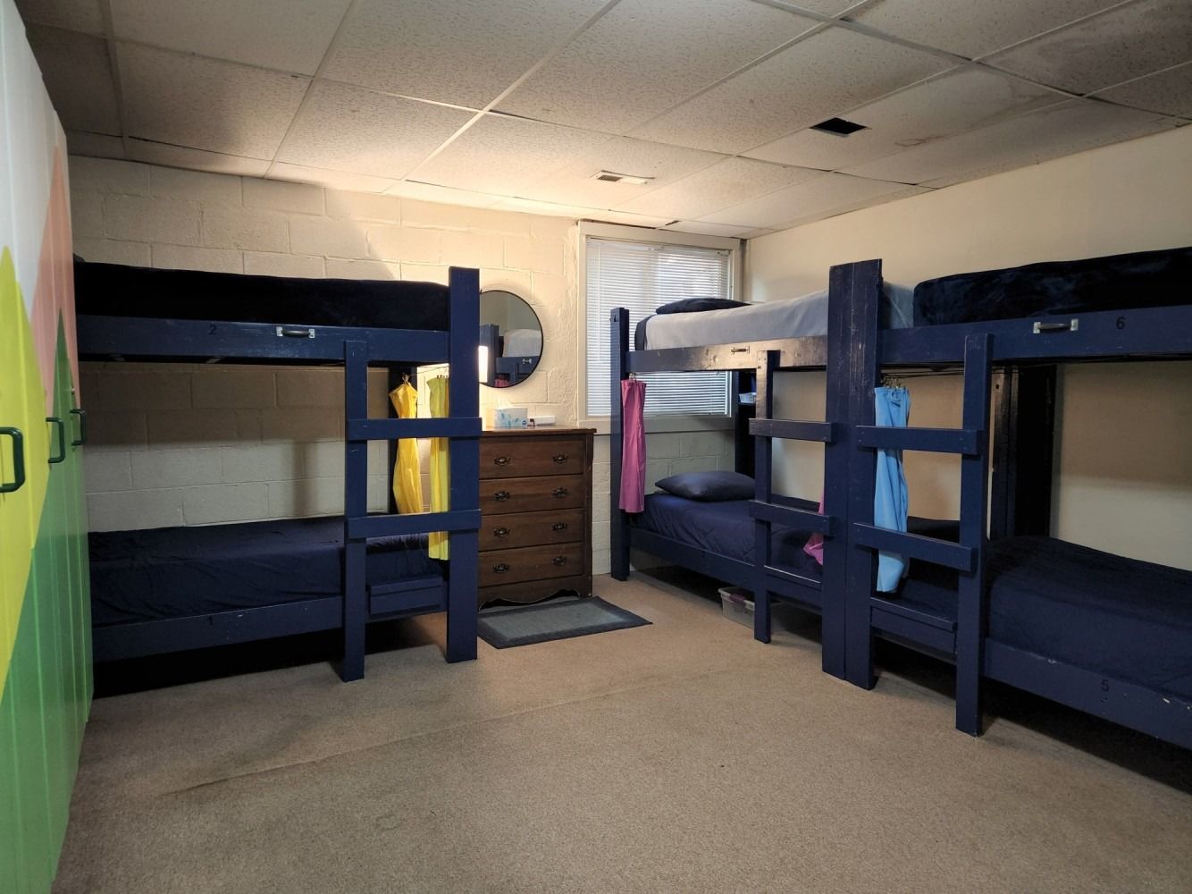 A room with four bunk beds and a dresser