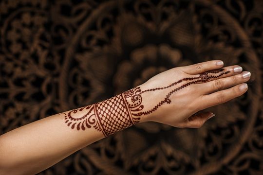 una donna ha un tatuaggio di henné sul polso e sul dito .