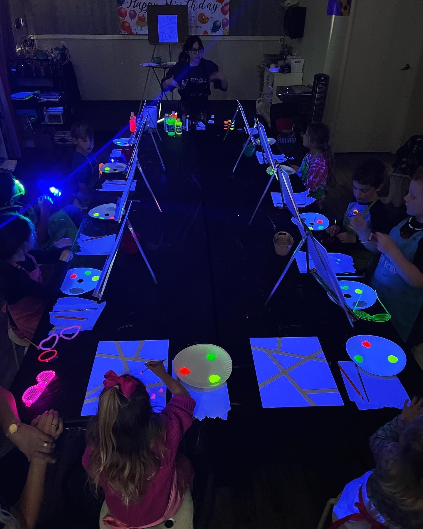 A group of children are sitting at a table with glow in the dark plates.