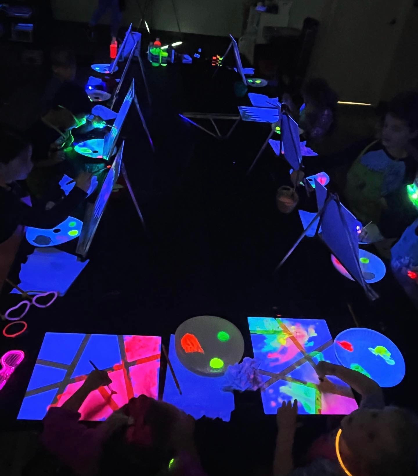 A group of children are painting with glow in the dark paint