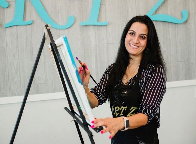 neelu kharbanda smiling and painting at easel