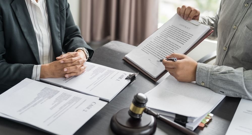 Lawyer reviewing documents with a client at a table, gavel present.