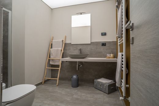 Un bagno con wc, lavandino, specchio e portasciugamani.