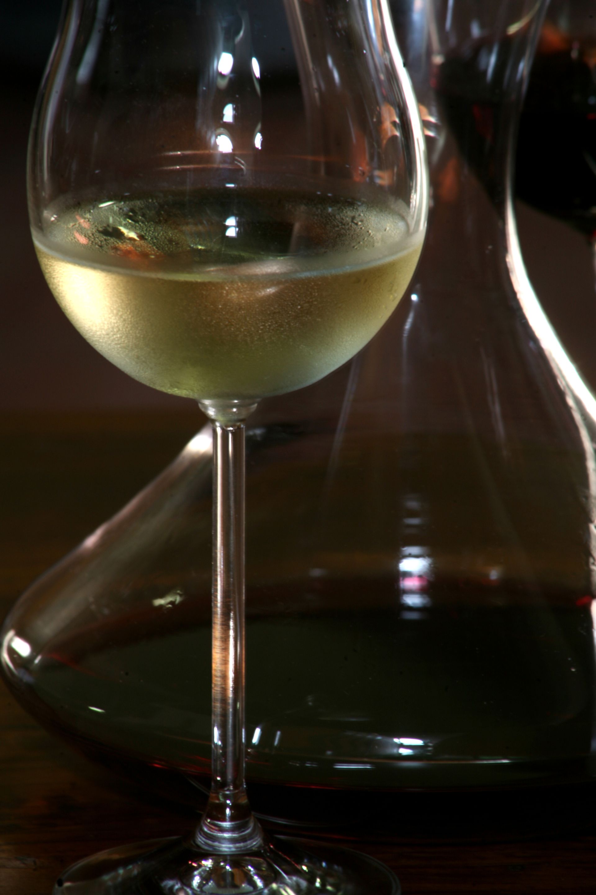 Una bottiglia di vino in una scatola di legno con un nastro rosso e due bicchieri da vino