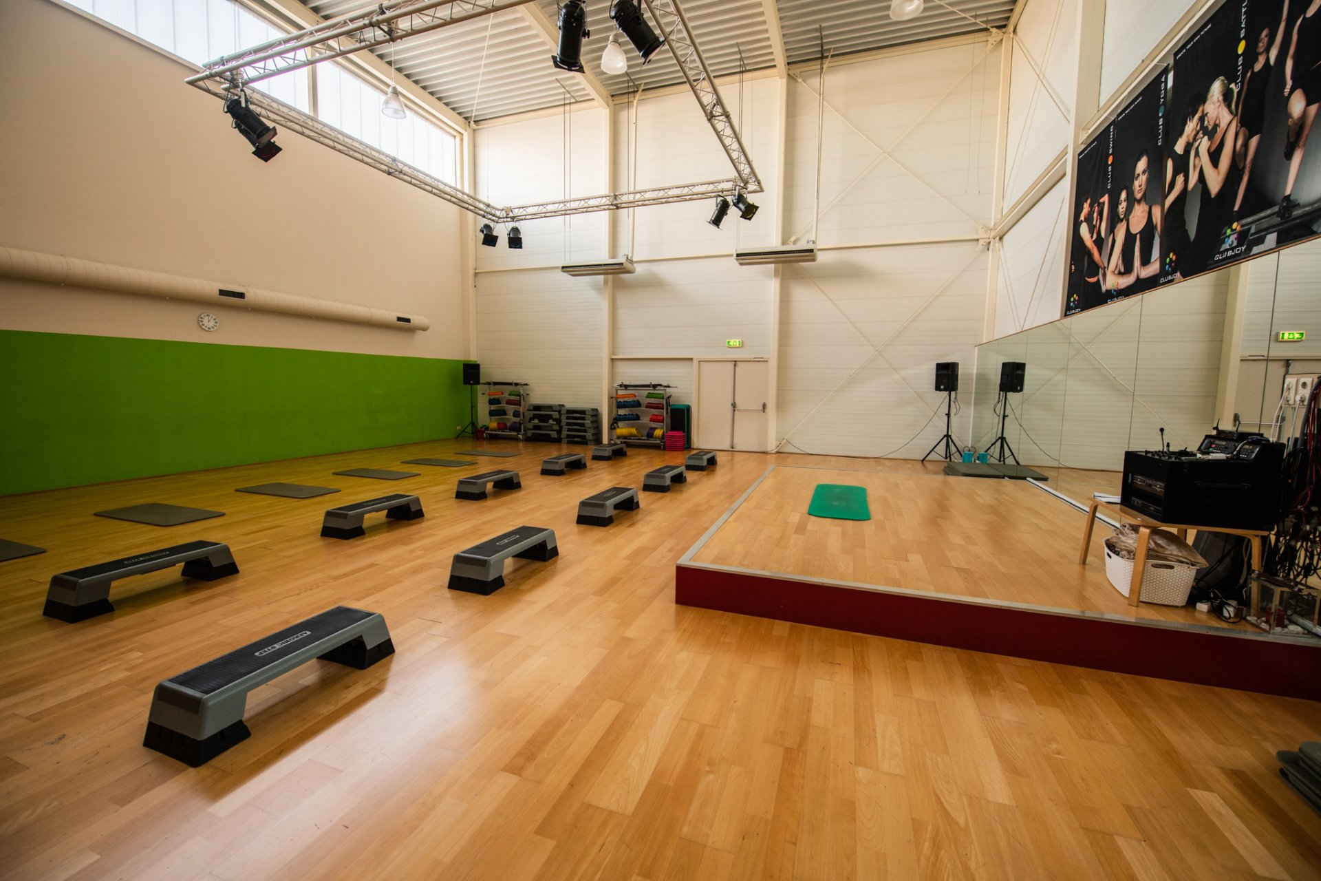 Een grote lege gymzaal met houten vloeren en een podium.