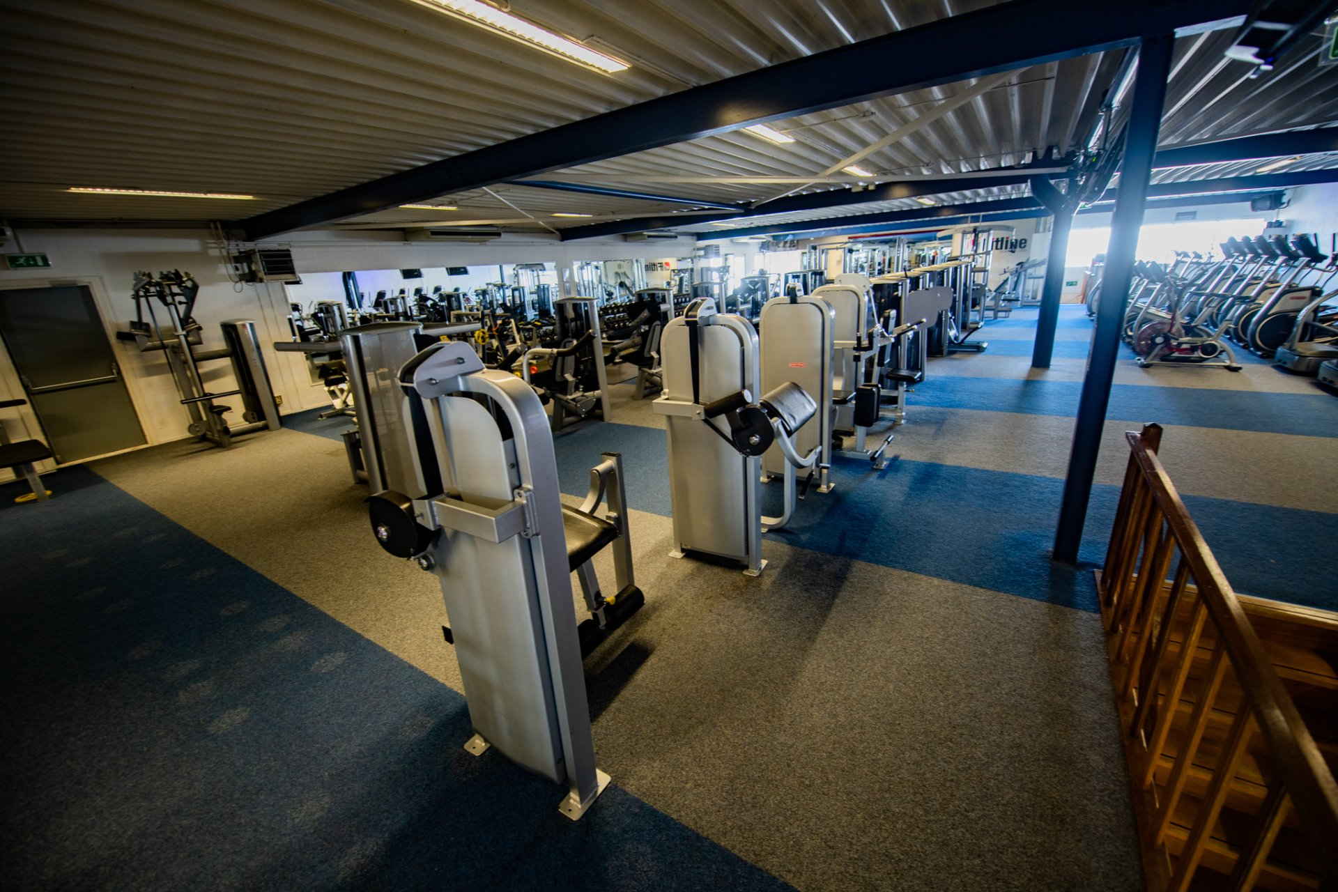 Een grote fitnessruimte vol met veel fitnessapparatuur