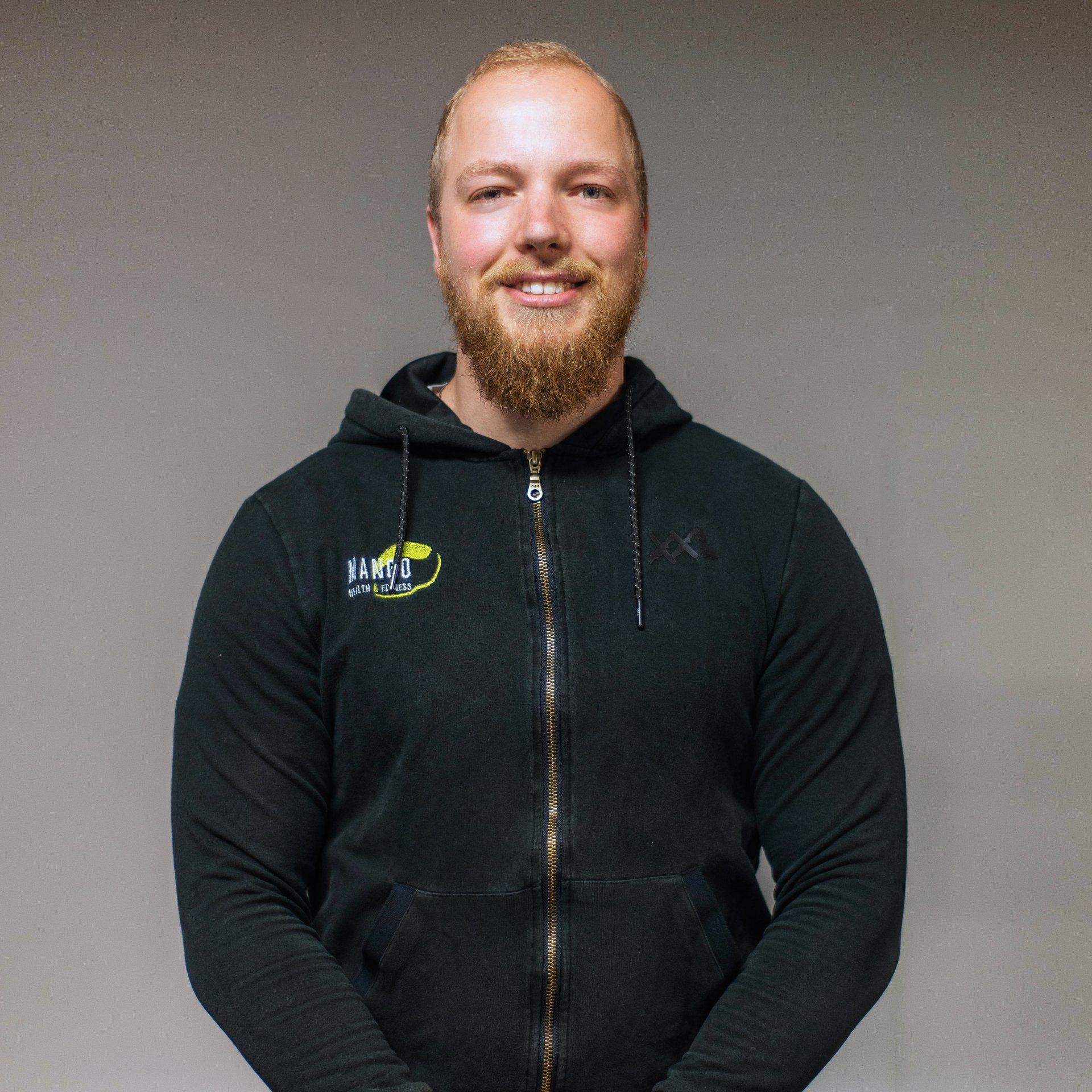 Een man met een baard draagt ​​een zwarte hoodie met het woord tmt erop