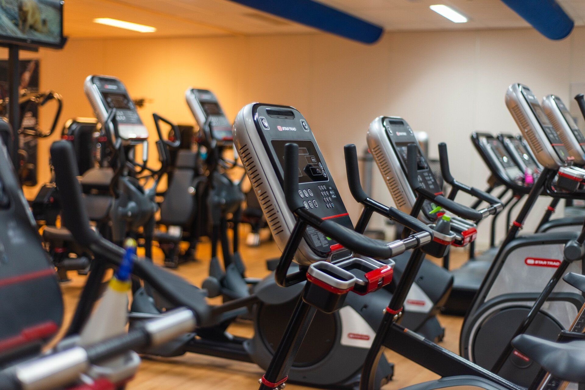 Een sportschool vol met veel fitnessapparatuur, waaronder loopbanden en elliptische trainers.