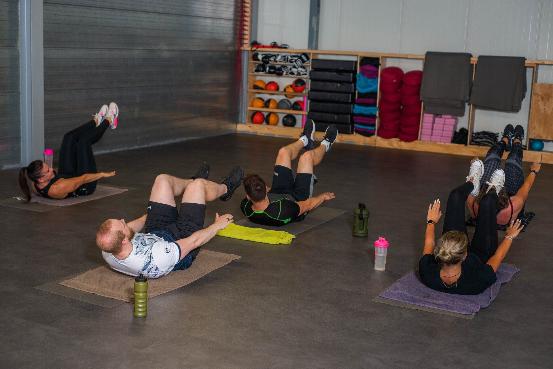 Een groep mensen doet oefeningen op de vloer in een sportschool.