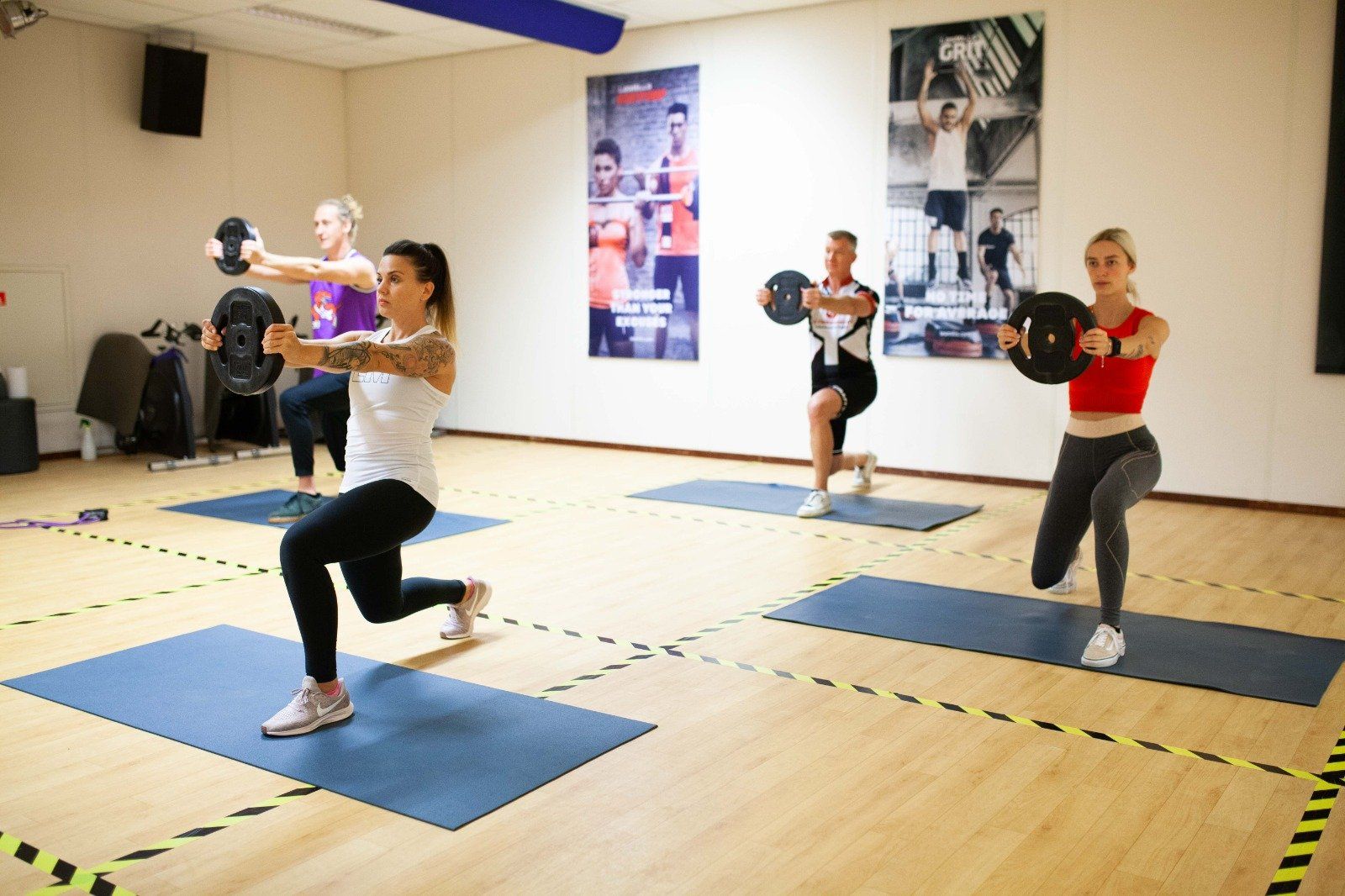 Een groep vrouwen doet squats op yogamatten in een sportschool.