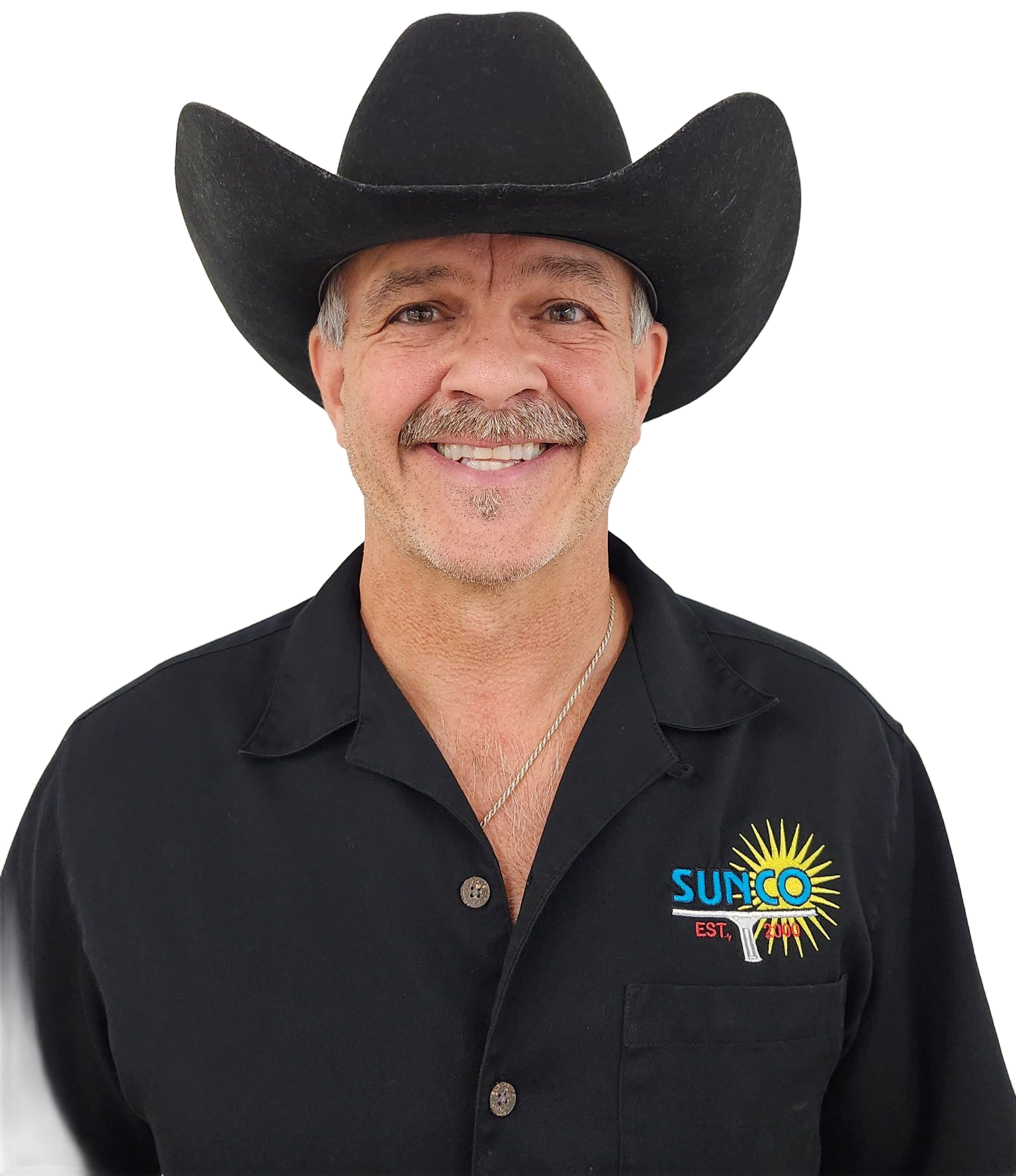 A man wearing a hat and a black shirt is standing in front of a white wall.