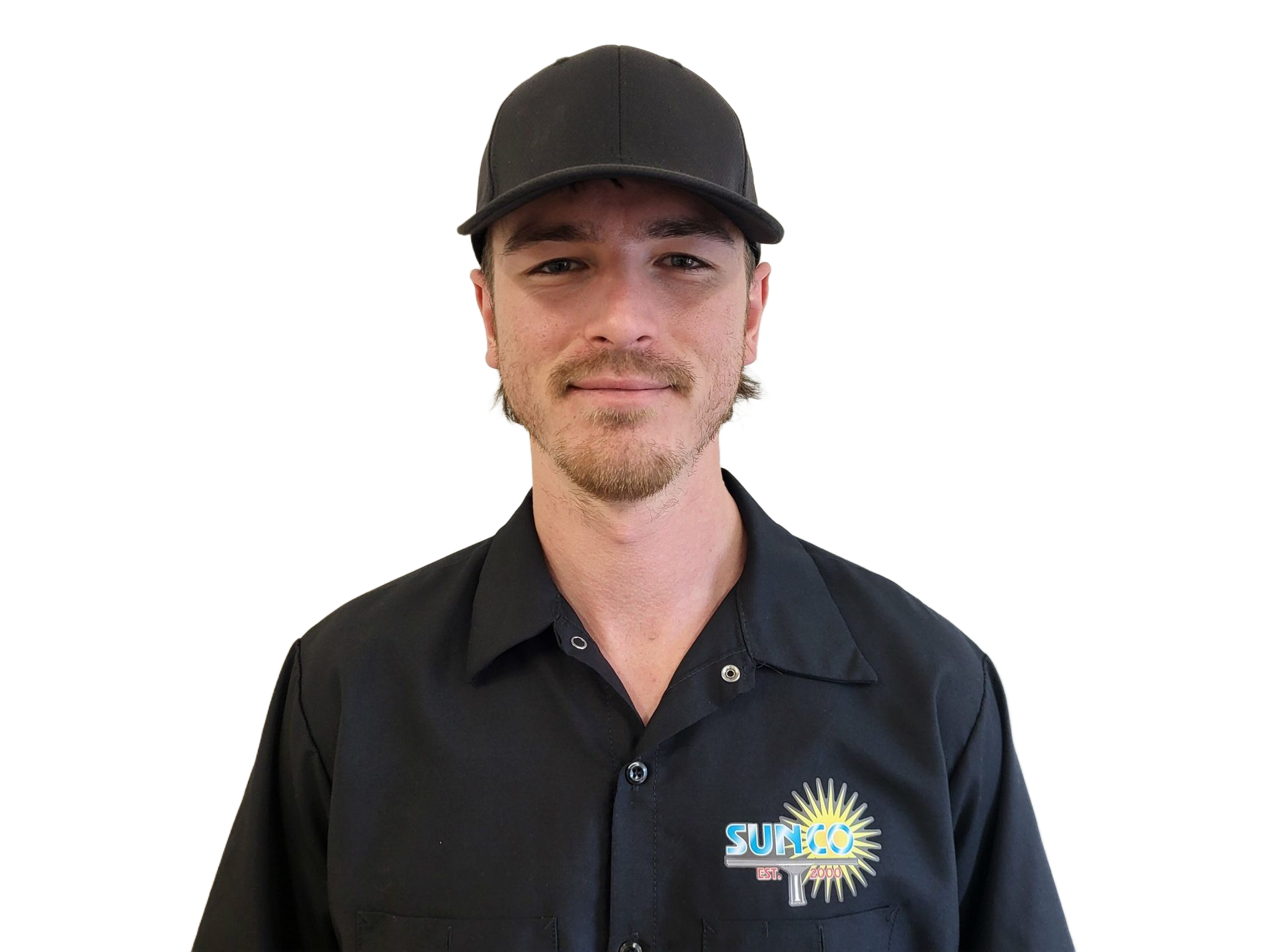 A man wearing a hat and a black shirt is standing in front of a white wall.