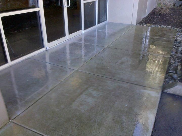 A concrete walkway in front of a building with a glass door